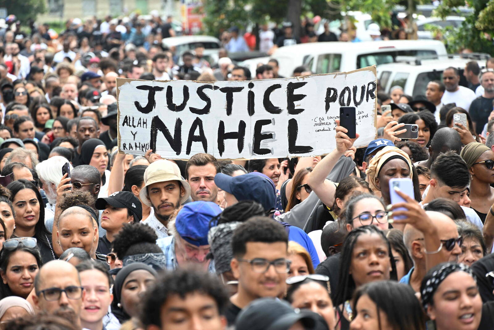 TOPSHOT - Attendees hold a banner reading "Justice for Nahel", during a commemoration march for a teenage driver shot dead by a policeman, in the Pablo Picasso area of the Parisian suburb of Nanterre, on June 29, 2023. Violent protests broke out in France in the early hours of June 29, 2023, as anger grows over the police killing of a teenager, with security forces arresting 150 people in the chaos that saw balaclava-clad protesters burning cars and setting off fireworks. Nahel M., 17, was shot in the chest at point-blank range in Nanterre in the morning of June 27, 2023, in an incident that has reignited debate in France about police tactics long criticised by rights groups over the treatment of people in low-income suburbs, particularly ethnic minorities. (Photo by Bertrand GUAY / AFP)